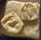 Two cream knitted blankets/hats for a baby on a table