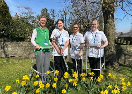 A photo of some of the therapy team with some walking aids in the spring sunshine with daffodils in bloom