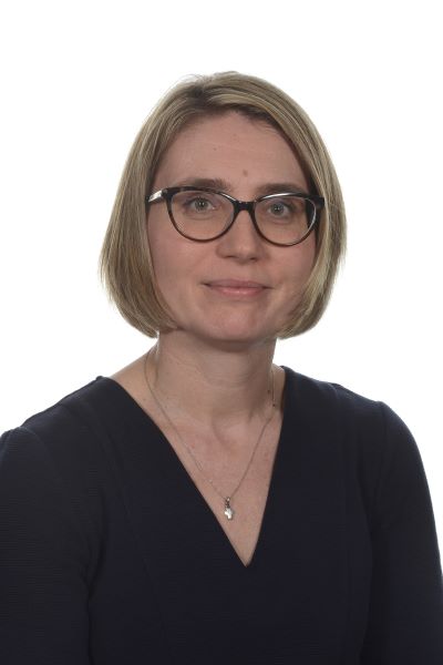 A person wearing glasses and a black v-neck top.