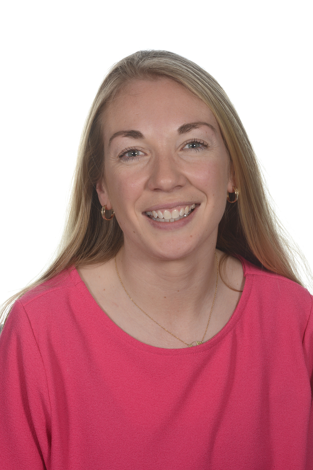 A woman smiling with blonde hair and in a pink top.