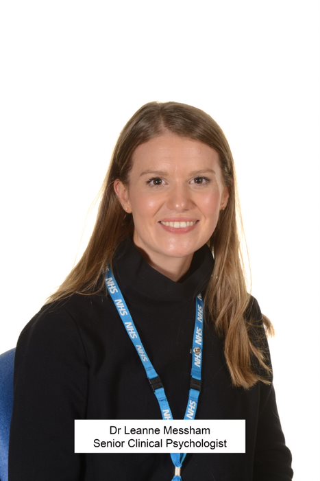 A person in a black top with long brown hair smiles for a picture.