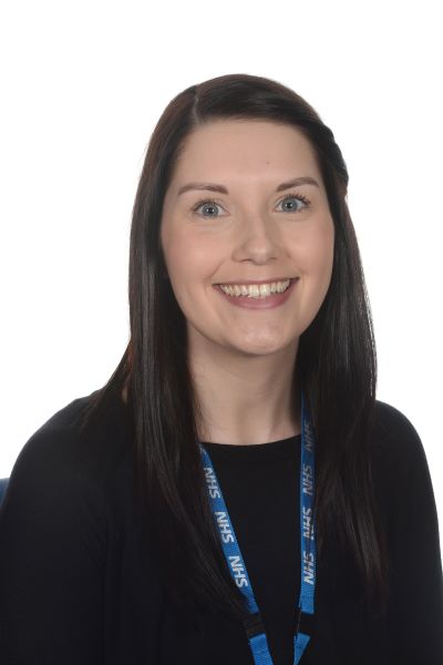 A person in a black top with long black hair smiles for a picture.