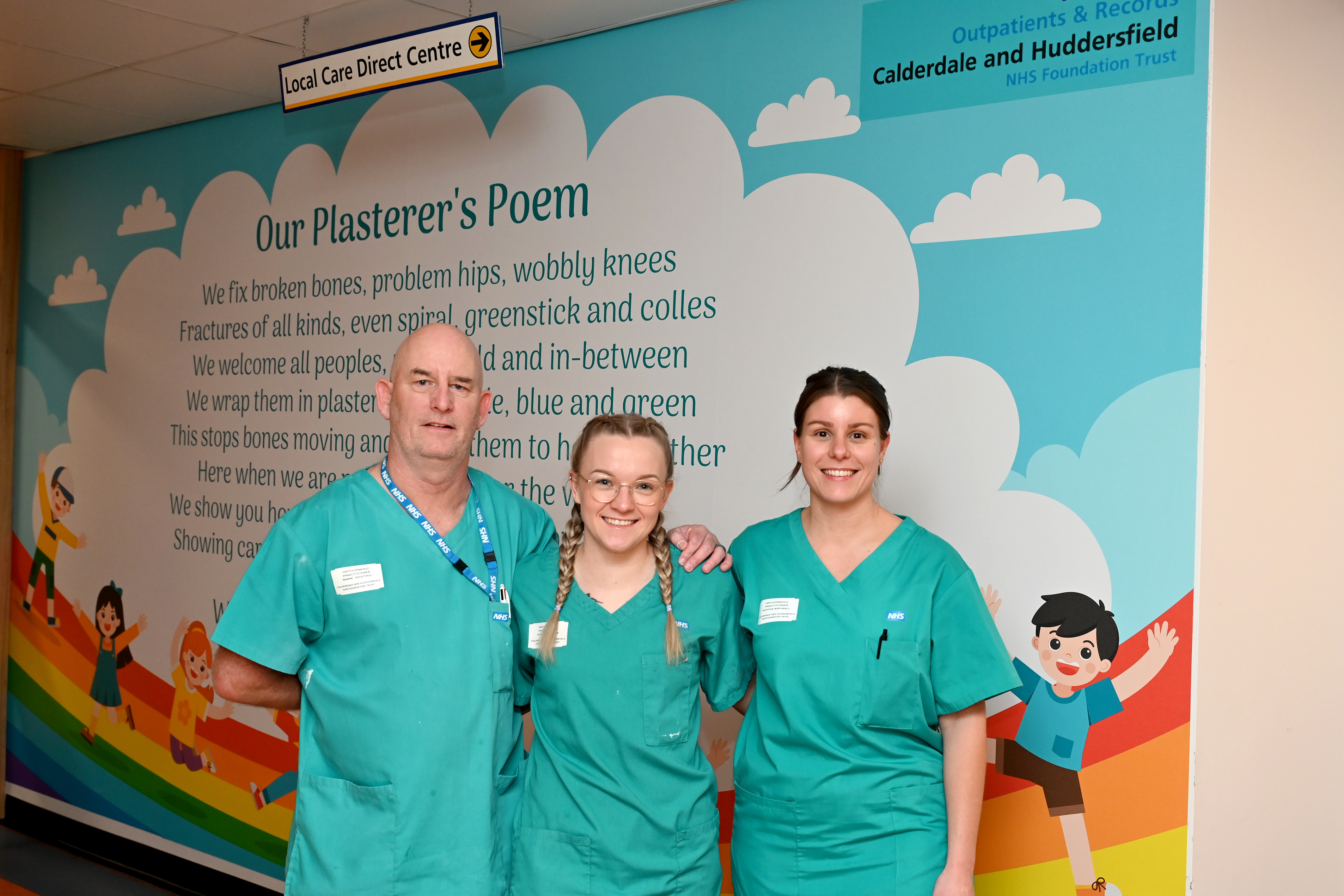 Three individuals, dressed in cyan scrubs, are posing for a photo.