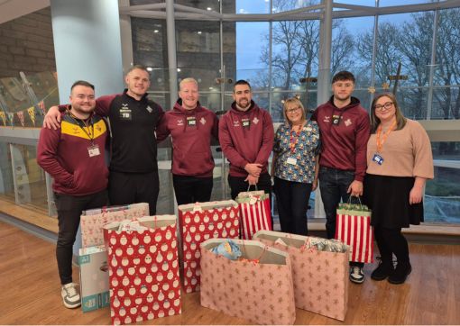 Players from the Huddersfield Giants standing with staff and the gifts they'd come to donate