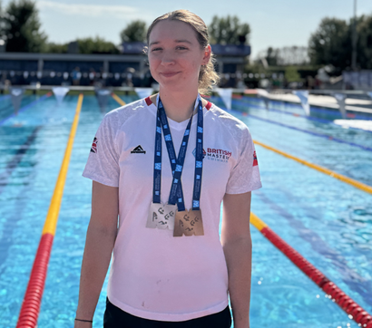 Georgia stood in front of an outdoor pool with her medals