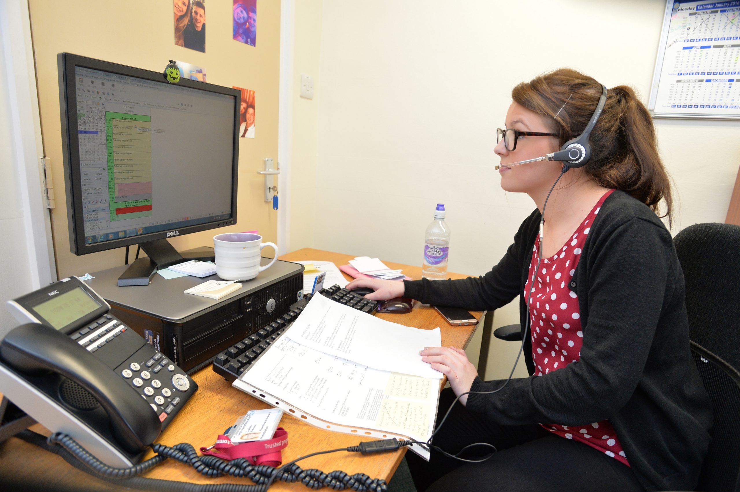 A woman sat working at a desk with a headset on.