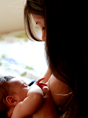 Mother holding newborn baby while breastfeeding.