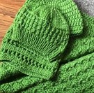 Two green knitted blankets/hats for a baby on a surface
