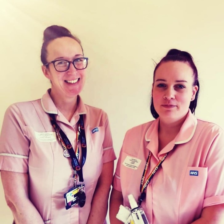 Two people wearing pink uniforms and badges