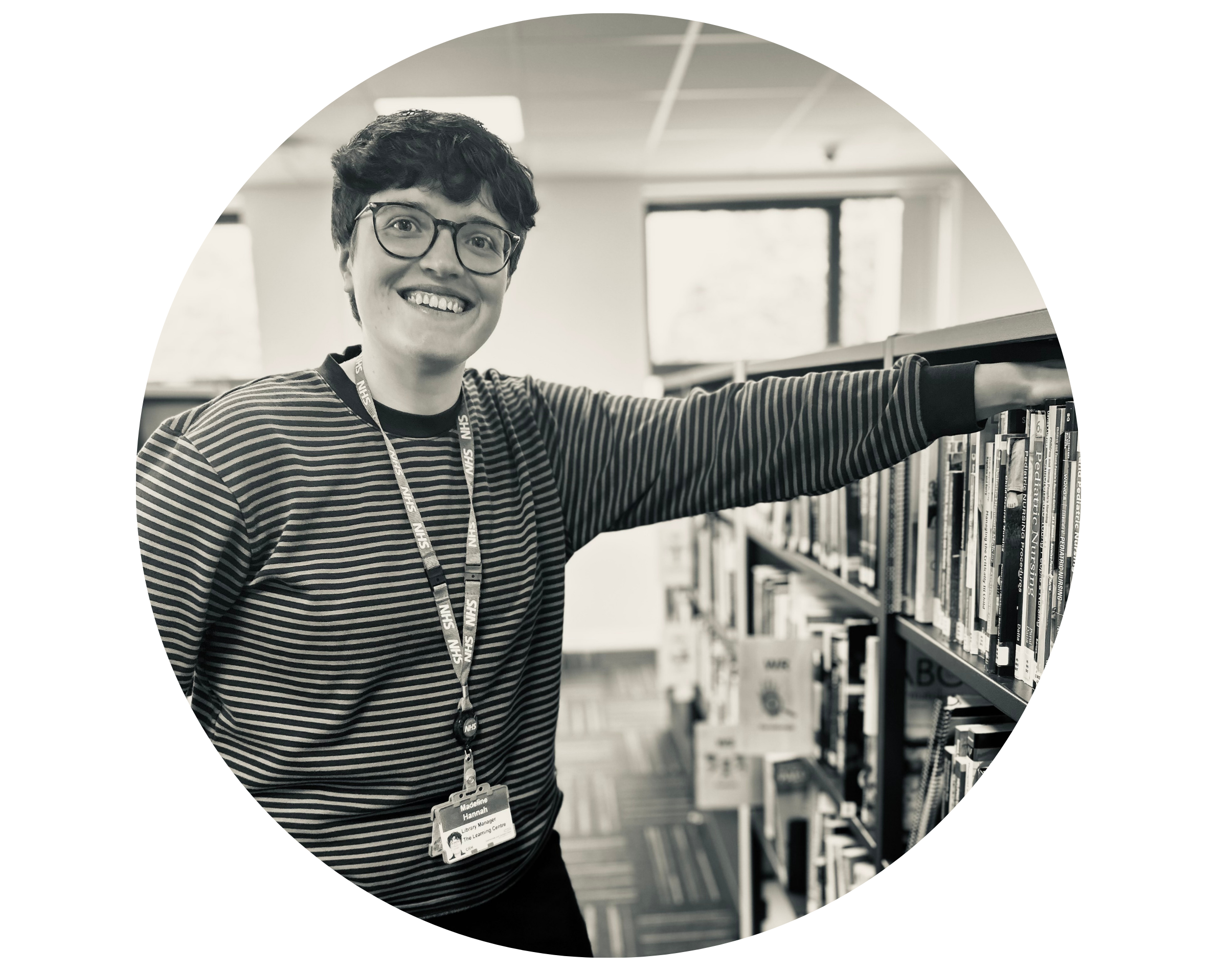 Black and white photo of Library Manager Madeline standing next to a bookshelf.