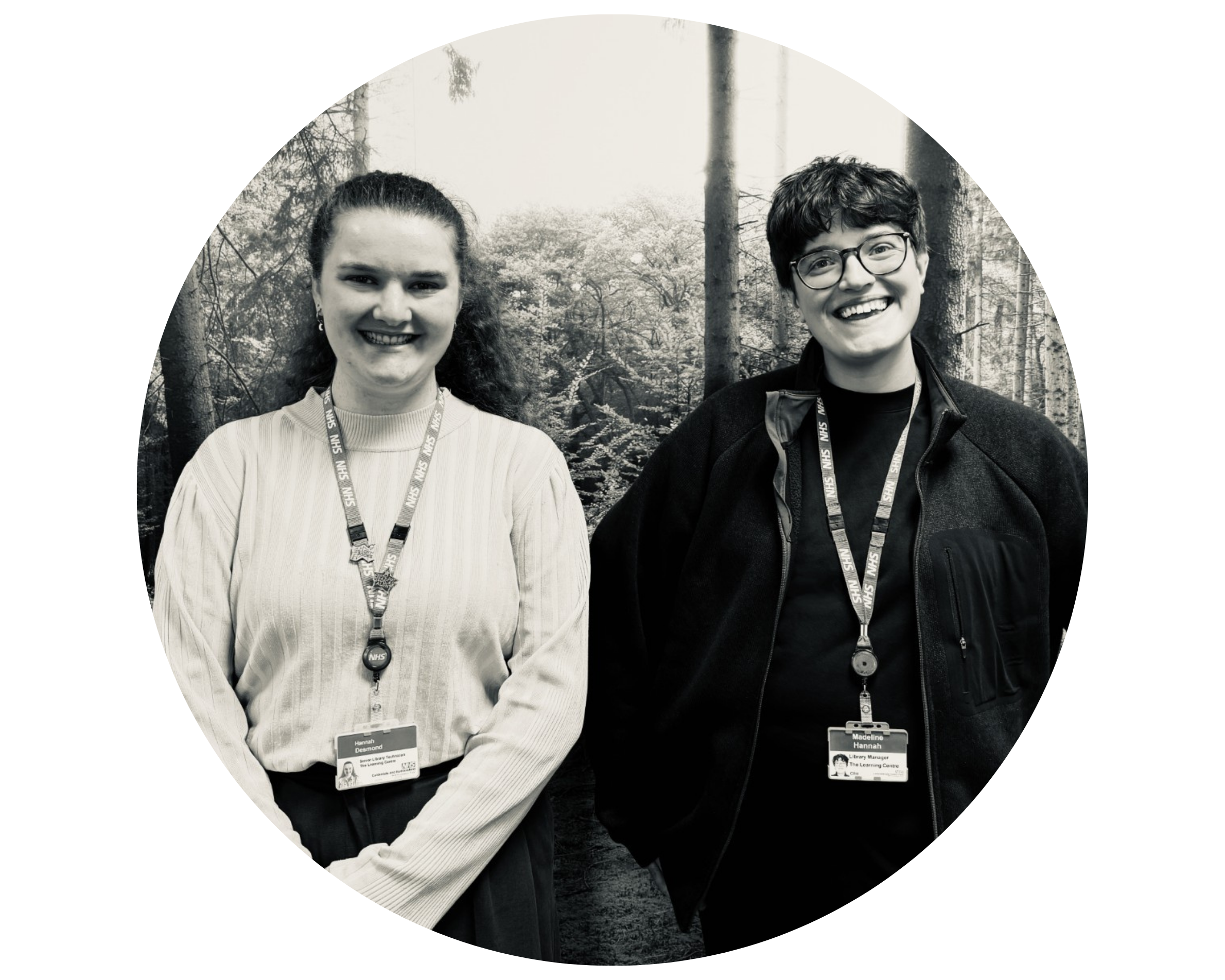 Black and white photo of Madeline and Hannah standing against a wall with a picture of trees.