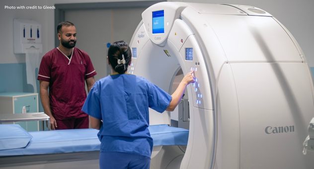 Two healthcare professionals stand by a CT scanner