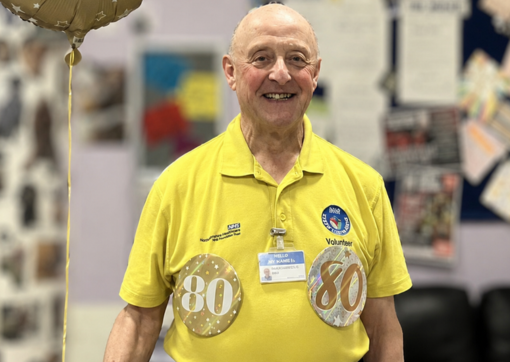 Volunteer Phil with his 80 badges smiling on his birthday