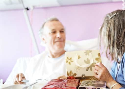 Male patient sat with female visitor opening gifts